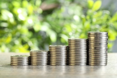 Photo of Salary concept. Stacked coins on grey table against blurred background