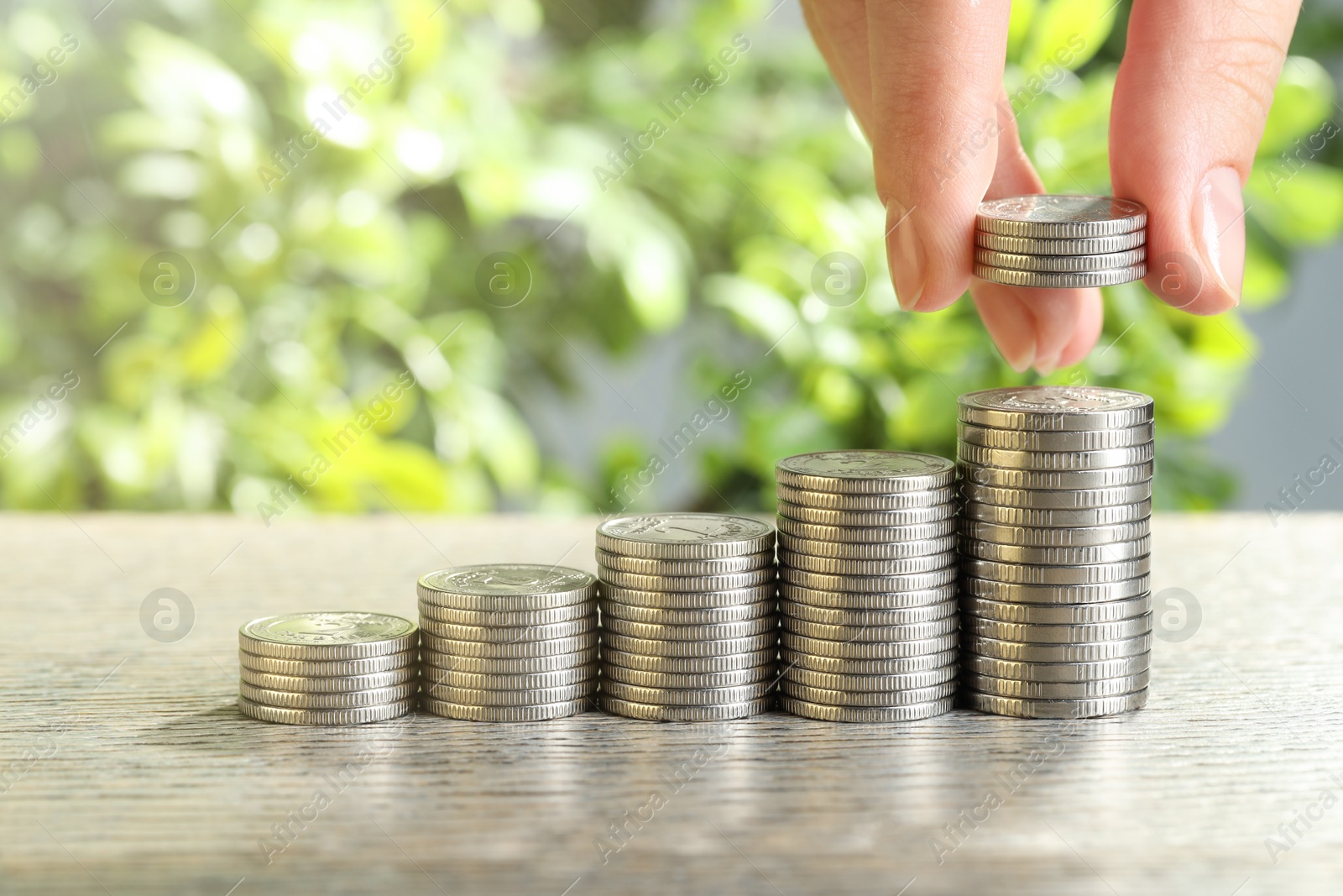 Photo of Salary concept. Woman putting coins on stack at grey table, closeup