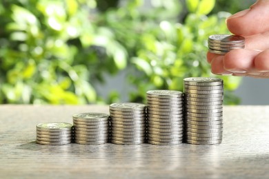 Photo of Salary concept. Woman putting coins on stack at grey table, closeup