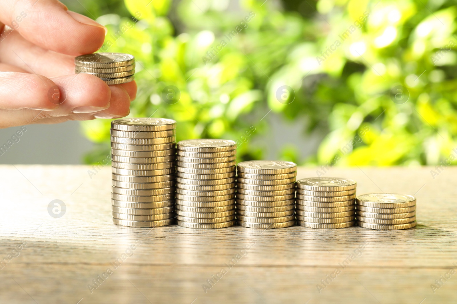 Photo of Salary concept. Woman putting coins on stack at grey table, closeup