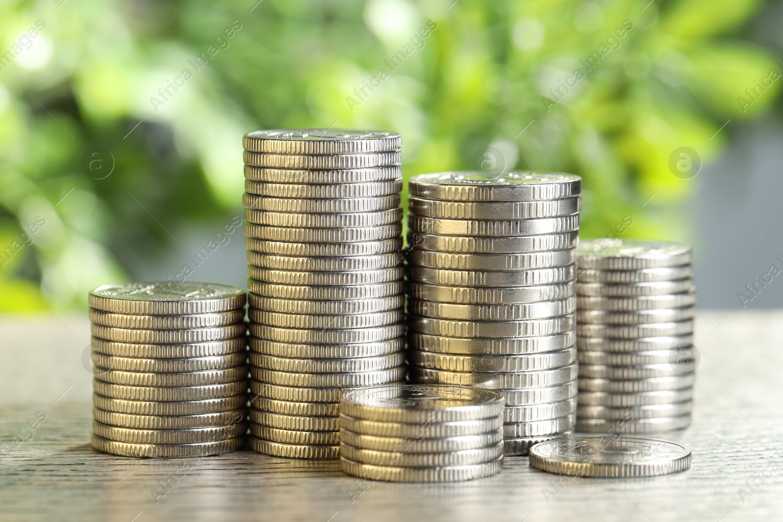 Photo of Salary concept. Stacked coins on grey table against blurred background