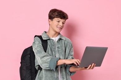 Photo of Happy teenage boy with laptop and backpack on pink background