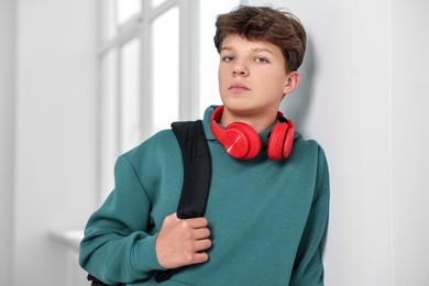 Teenage boy with headphones and backpack indoors