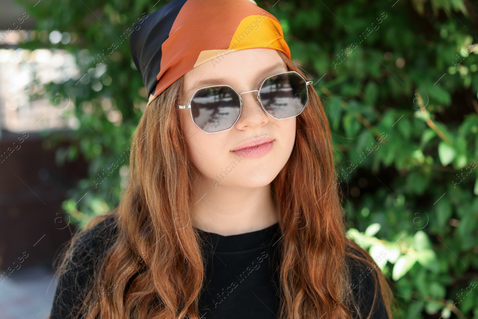 Photo of Portrait of happy teenage girl with long hair wearing sunglasses and bandana outdoors