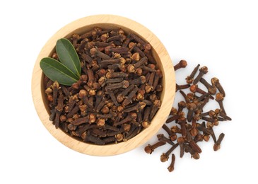 Photo of Dry clove buds and green leaves in wooden bowl on white background, top view. Aromatic spice