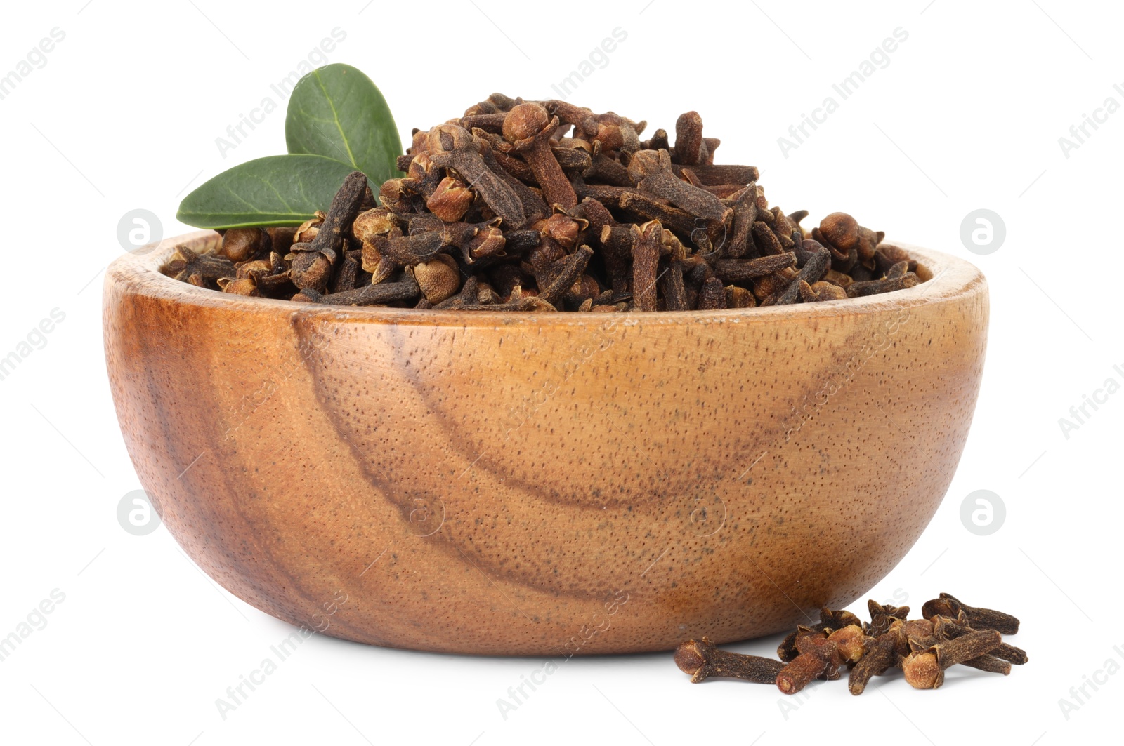 Photo of Dry clove buds and green leaves in wooden bowl on white background. Aromatic spice