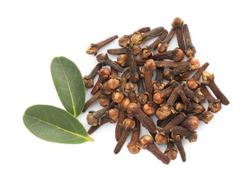 Dry clove buds and green leaves on white background, top view. Aromatic spice