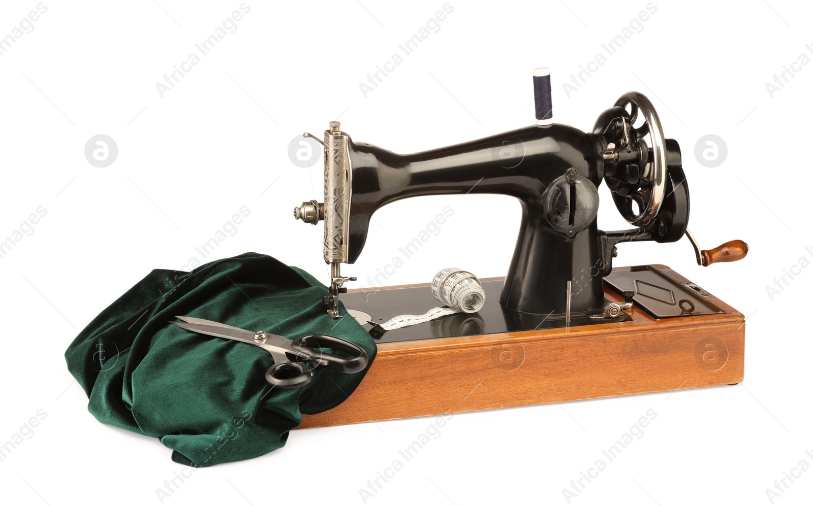 Photo of Sewing machine with green fabric, measuring tape, scissors and spools of threads isolated on white