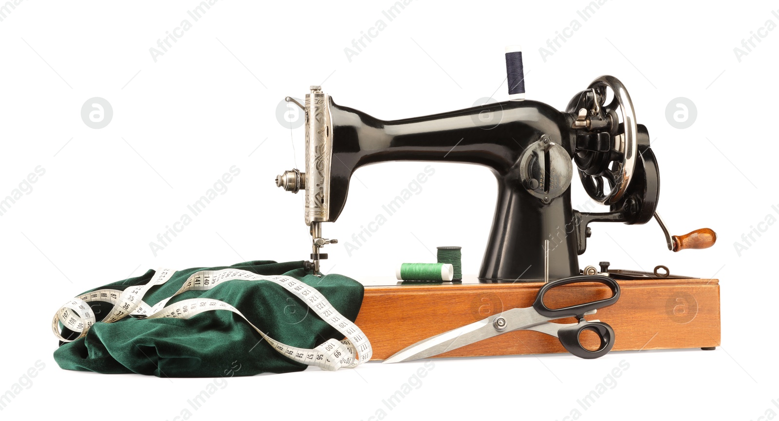 Photo of Sewing machine with green fabric, measuring tape, scissors and spools of threads isolated on white