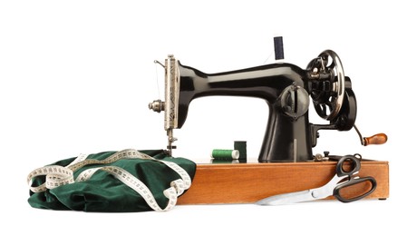 Photo of Sewing machine with green fabric, measuring tape, scissors and spools of threads isolated on white