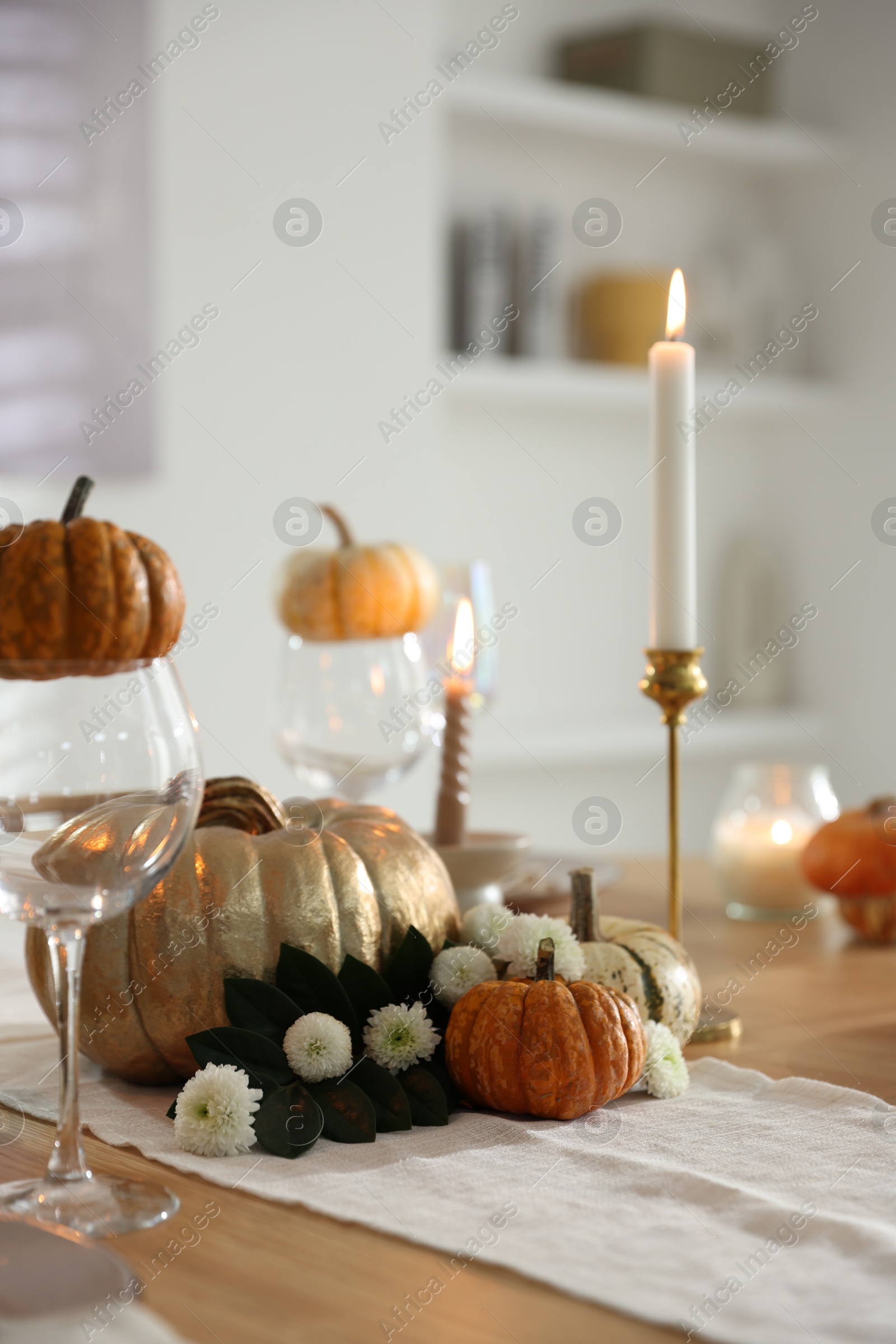 Photo of Stylish table setting with glasses, candles and autumn decor in dining room