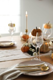 Stylish table setting with beautiful dishware, glasses and autumn decor in dining room