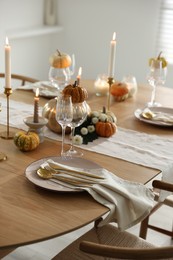 Stylish table setting with beautiful dishware, glasses and autumn decor in dining room