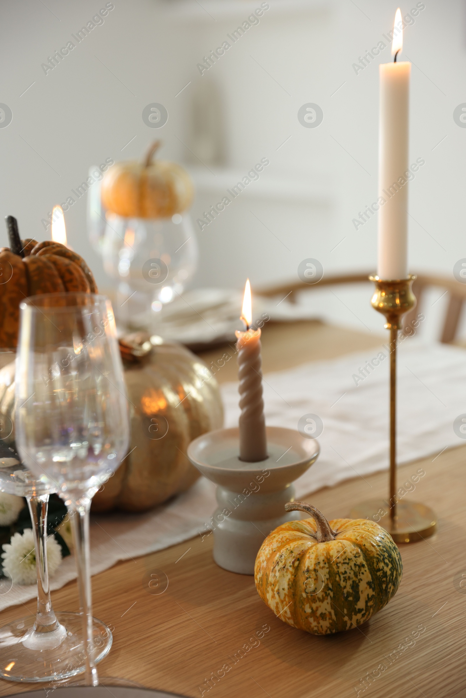 Photo of Stylish table setting with glasses, candles and autumn decor in dining room