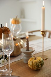 Stylish table setting with glasses, candles and autumn decor in dining room