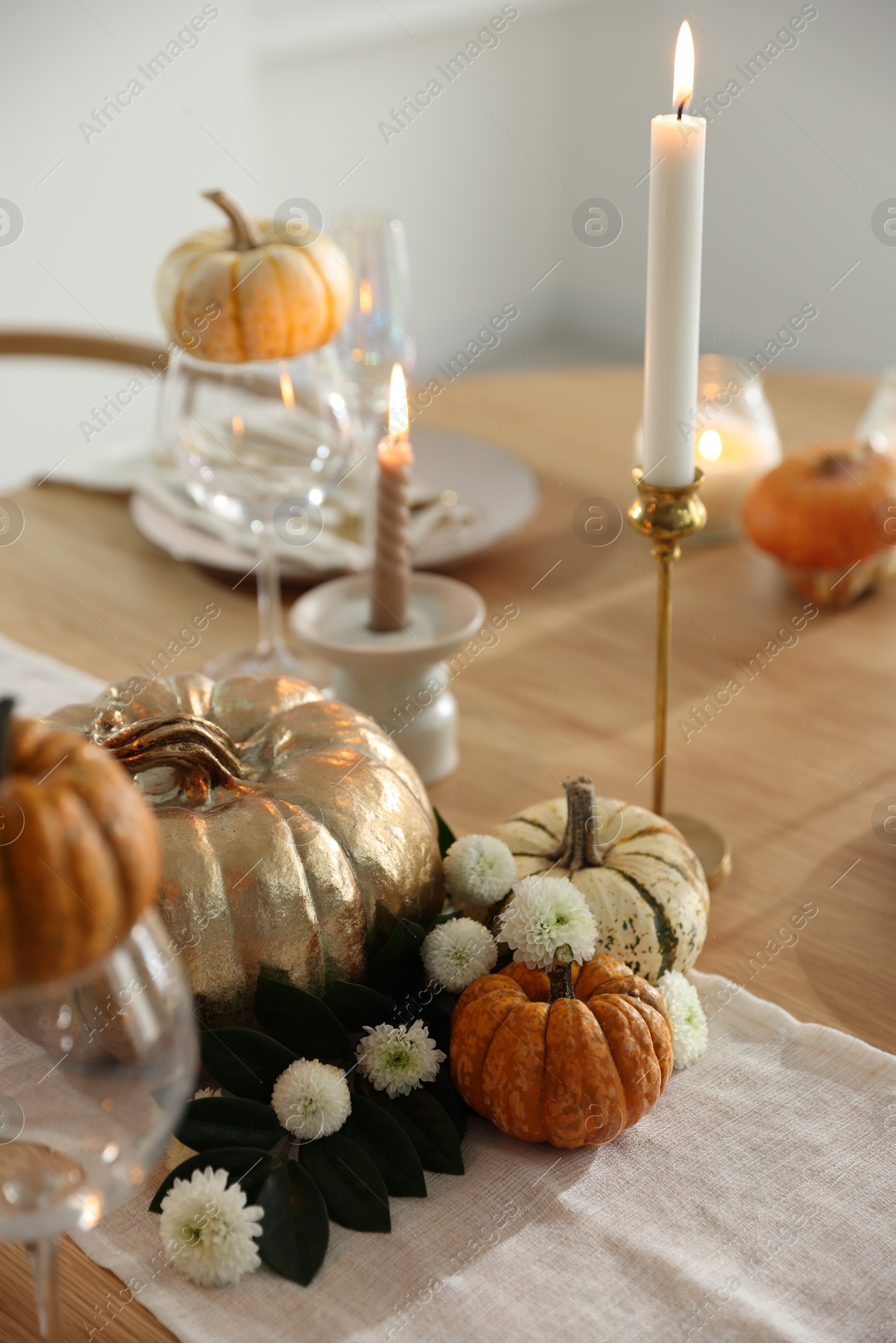 Photo of Stylish table setting with glasses, candles and autumn decor in dining room