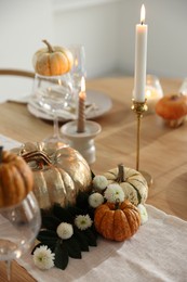 Stylish table setting with glasses, candles and autumn decor in dining room