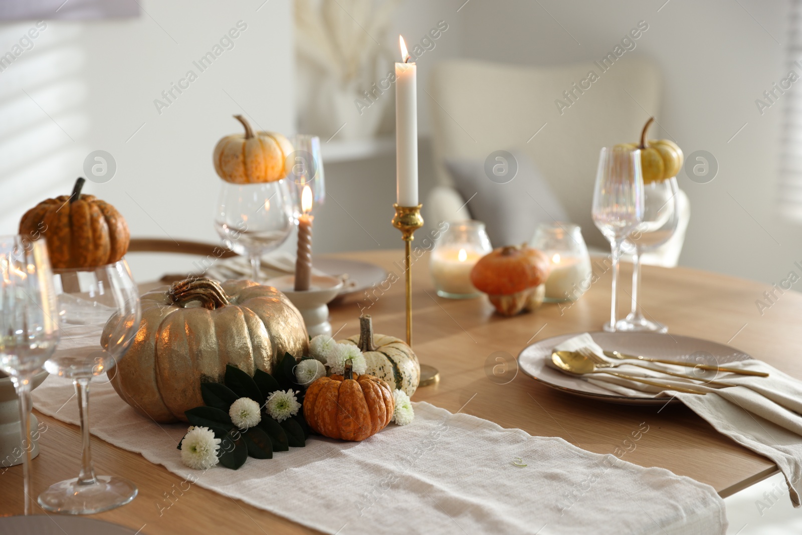 Photo of Stylish table setting with beautiful dishware, glasses and autumn decor in dining room