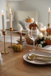 Stylish table setting with beautiful dishware, glasses and autumn decor in dining room