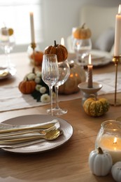 Stylish table setting with beautiful dishware, glasses and autumn decor in dining room