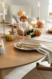 Stylish table setting with beautiful dishware, glasses and autumn decor in dining room