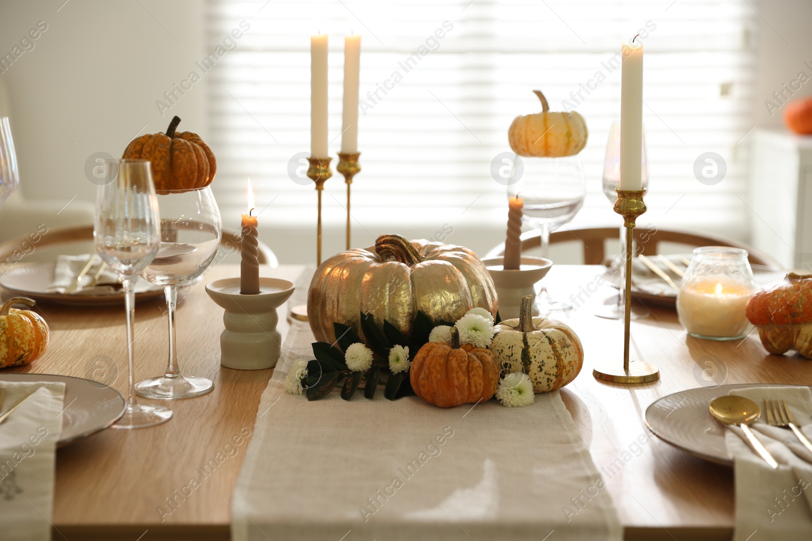 Photo of Stylish table setting with beautiful dishware, glasses and autumn decor in dining room