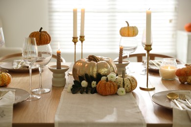 Stylish table setting with beautiful dishware, glasses and autumn decor in dining room