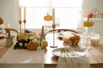 Stylish table setting with beautiful dishware, glasses and autumn decor in dining room