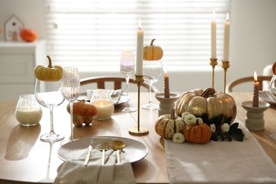 Stylish table setting with beautiful dishware, glasses and autumn decor in dining room