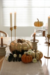 Stylish table setting with candles and autumn decor in dining room