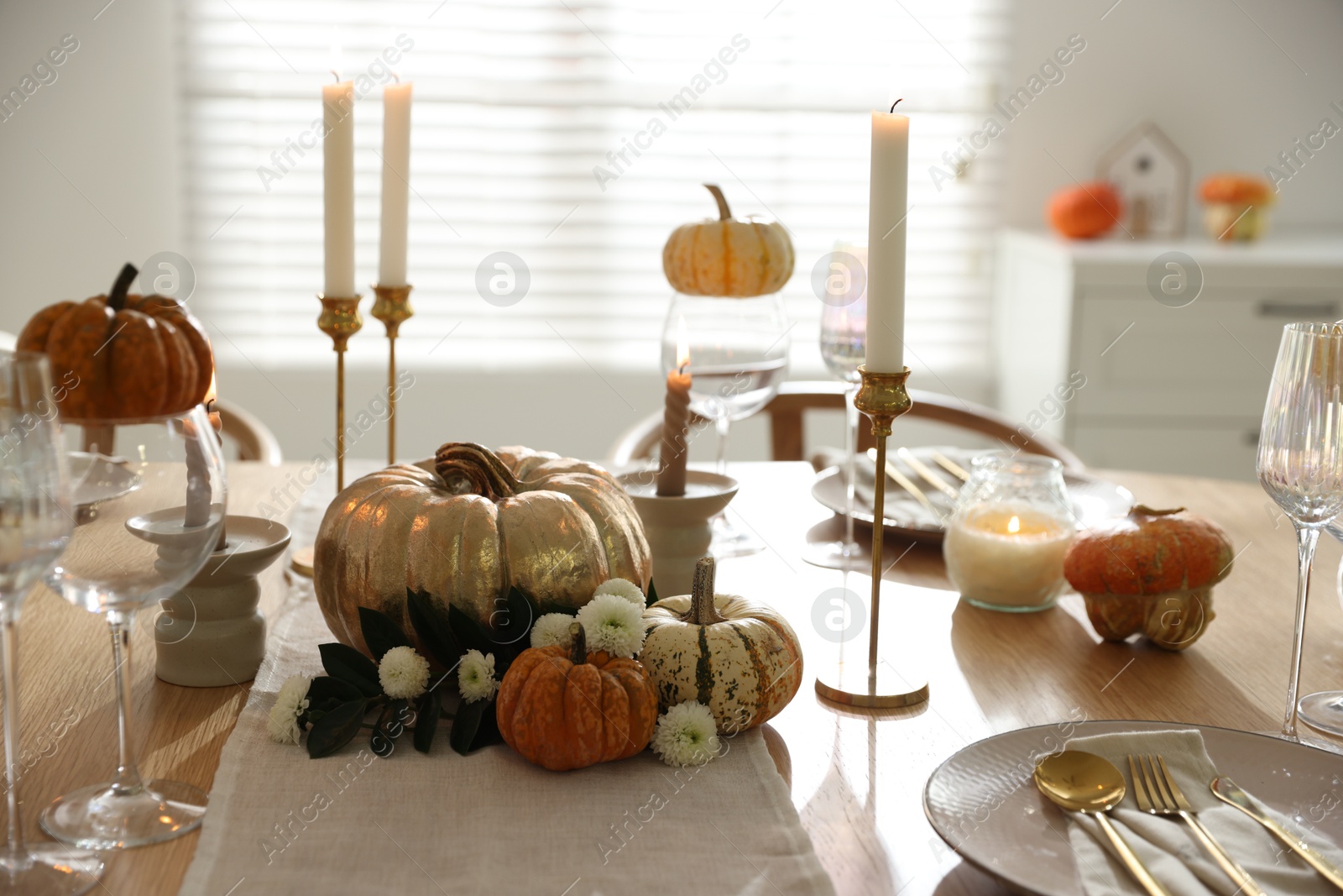 Photo of Stylish table setting with beautiful dishware, glasses and autumn decor in dining room