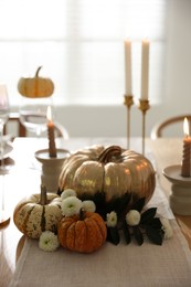 Stylish table setting with candles and autumn decor in dining room