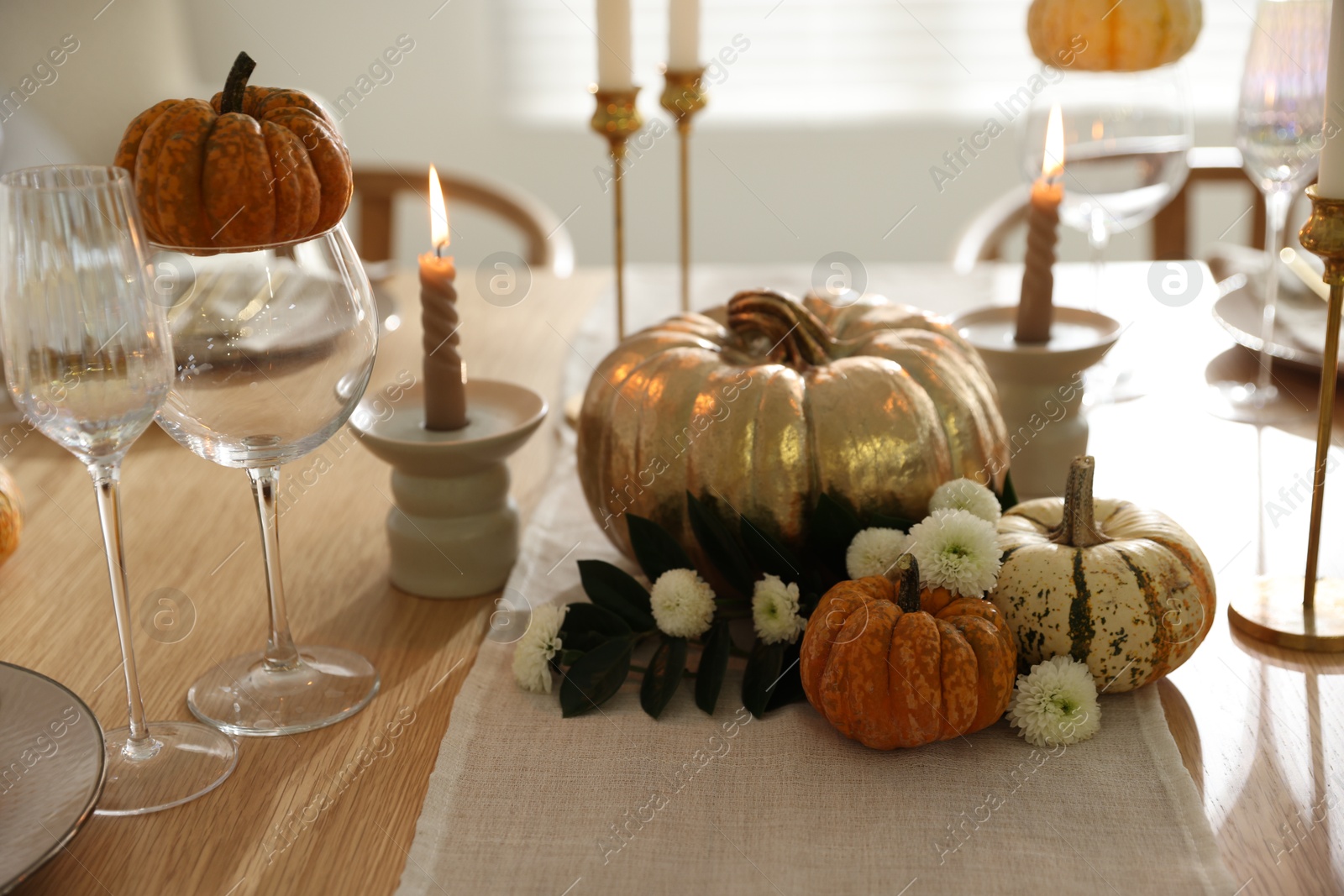 Photo of Stylish table setting with glasses, candles and autumn decor in dining room