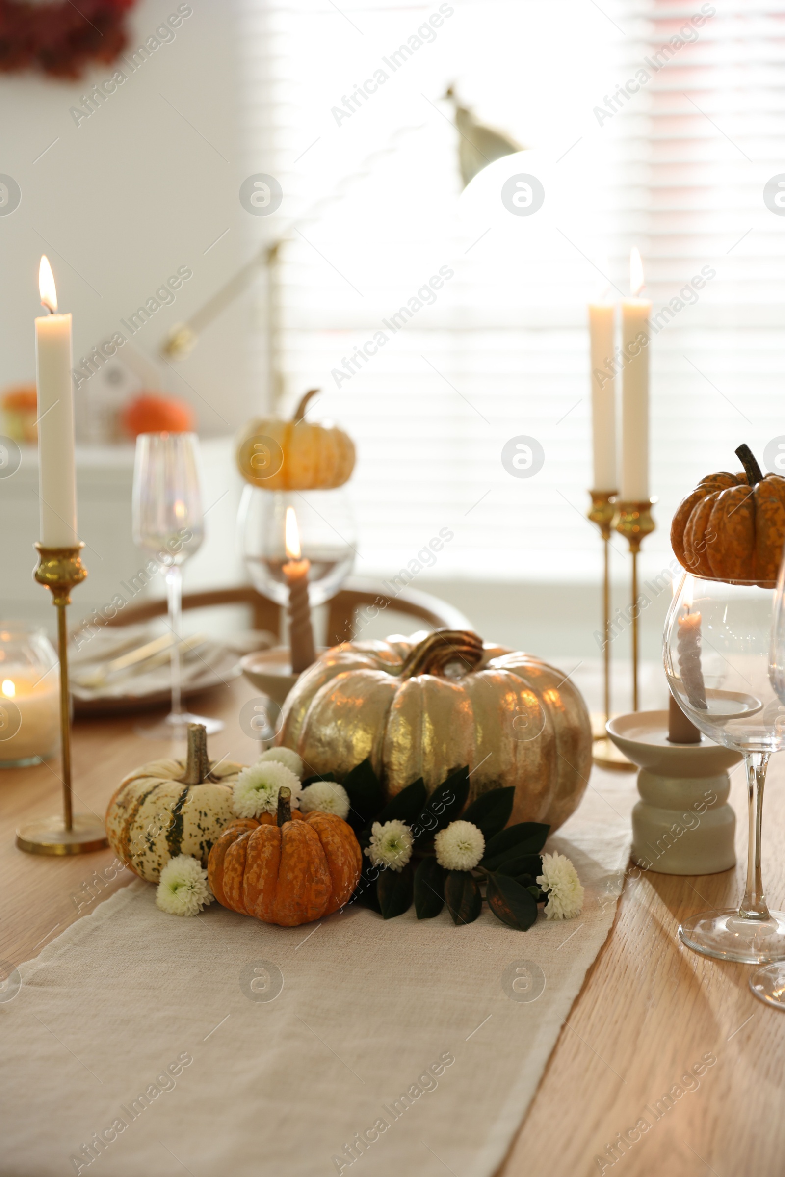 Photo of Stylish table setting with glasses, candles and autumn decor in dining room