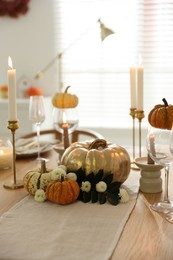 Stylish table setting with glasses, candles and autumn decor in dining room