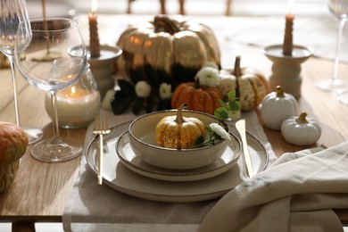 Photo of Stylish table setting with beautiful dishware, glasses and autumn decor in dining room