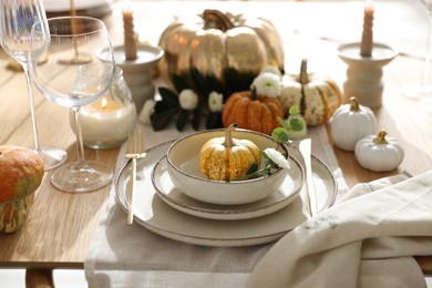 Stylish table setting with beautiful dishware, glasses and autumn decor in dining room