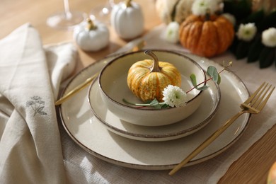 Photo of Stylish table setting with beautiful dishware and autumn decor in dining room, closeup