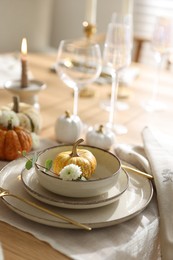 Stylish table setting with beautiful dishware, glasses and autumn decor in dining room