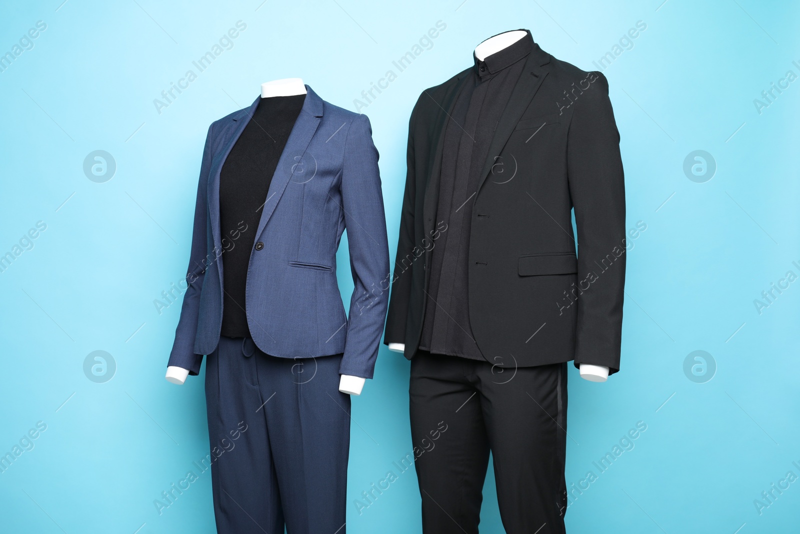 Photo of Female and male mannequins with stylish suits on light blue background