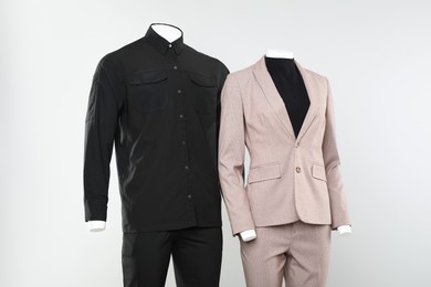 Female and male mannequins with stylish outfits on light background