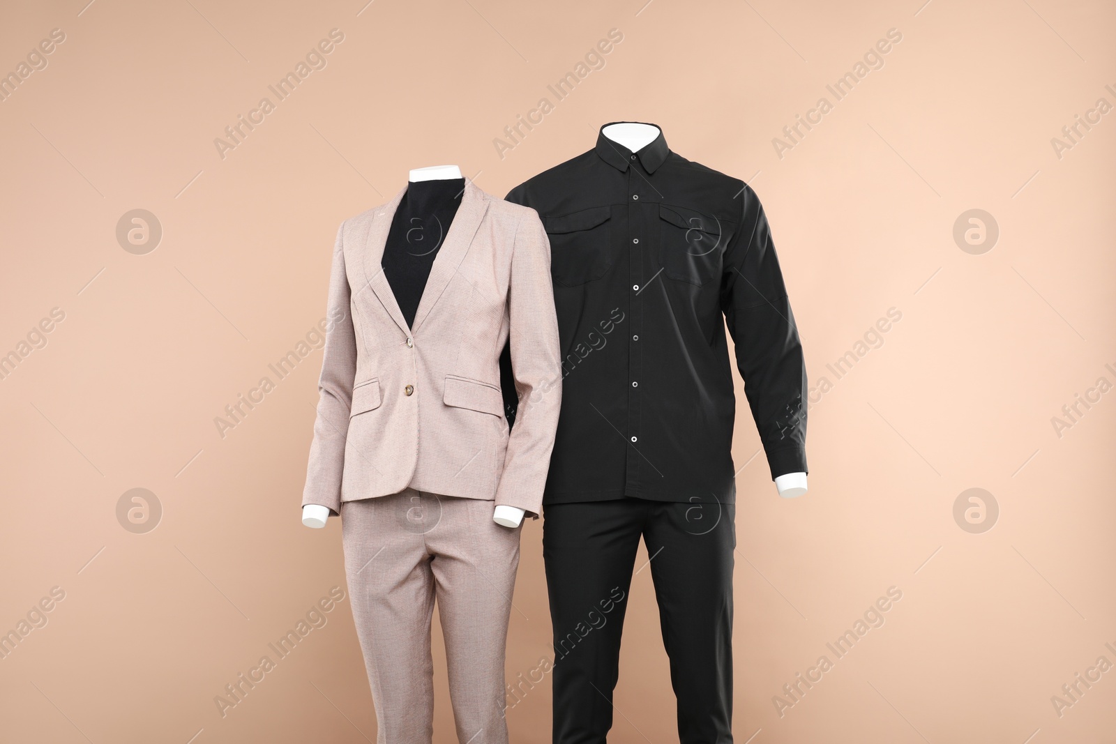 Photo of Female and male mannequins with stylish outfits on beige background