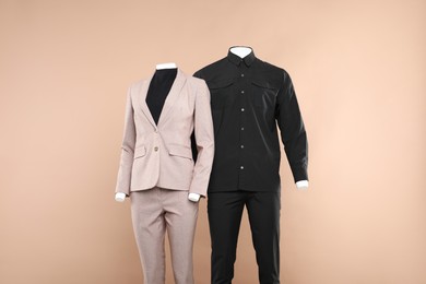 Photo of Female and male mannequins with stylish outfits on beige background