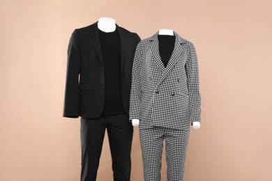 Female and male mannequins with stylish outfits on beige background