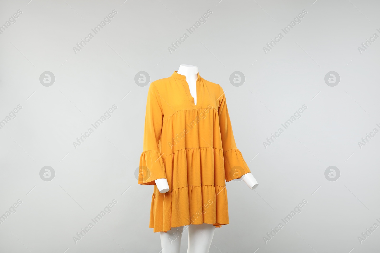 Photo of Female mannequin with stylish orange dress on light background