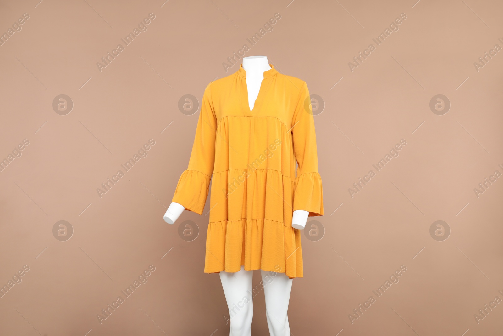 Photo of Female mannequin with stylish orange dress on beige background