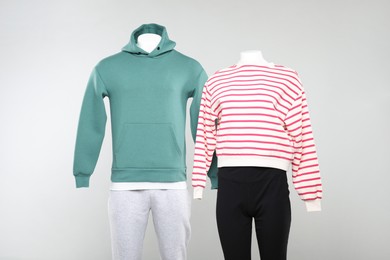 Photo of Female and male mannequins with stylish outfits on light background