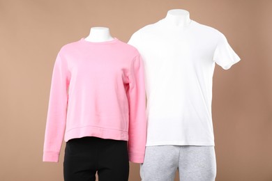 Photo of Female and male mannequins with stylish sportswear on beige background