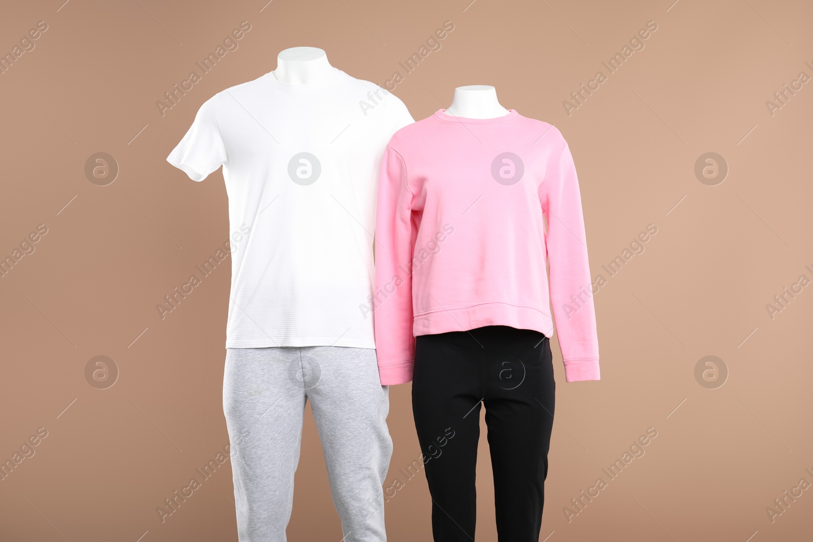 Photo of Female and male mannequins with stylish sportswear on beige background