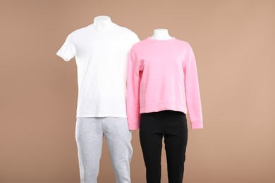 Female and male mannequins with stylish sportswear on beige background